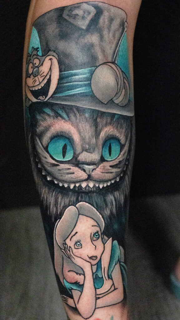 illustrative realism monochromatic tattoo of a Cheshire Cat and Alice from Alice and wonderland, greys and teals, done by Houston tattoo artist