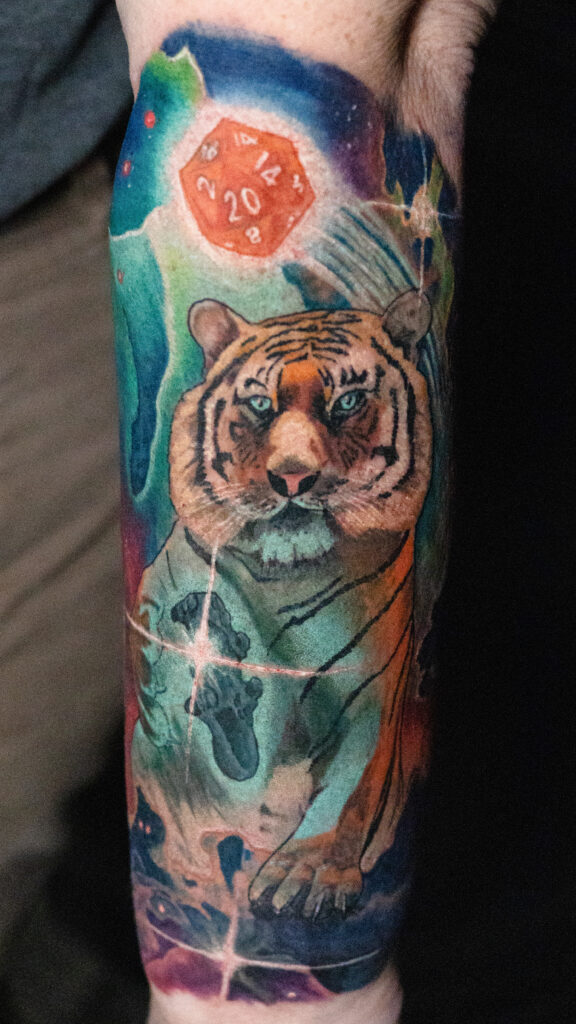color realism vibrant space tiger tattoo with a glowing gaming remote and a d20 die