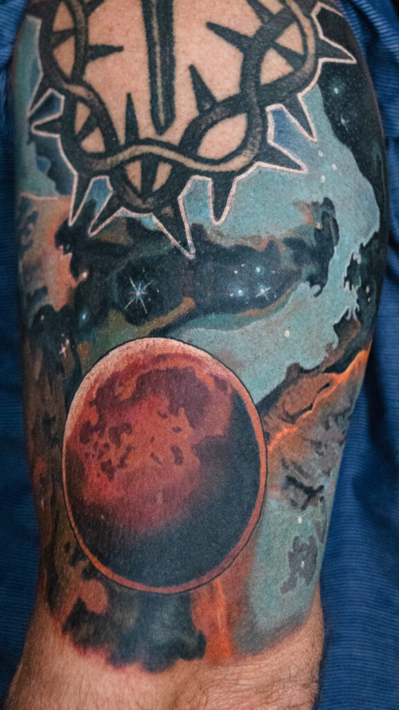 color realism space tattoo coverup done on an arm with a red planet and stars, done by a Houston tattoo artist