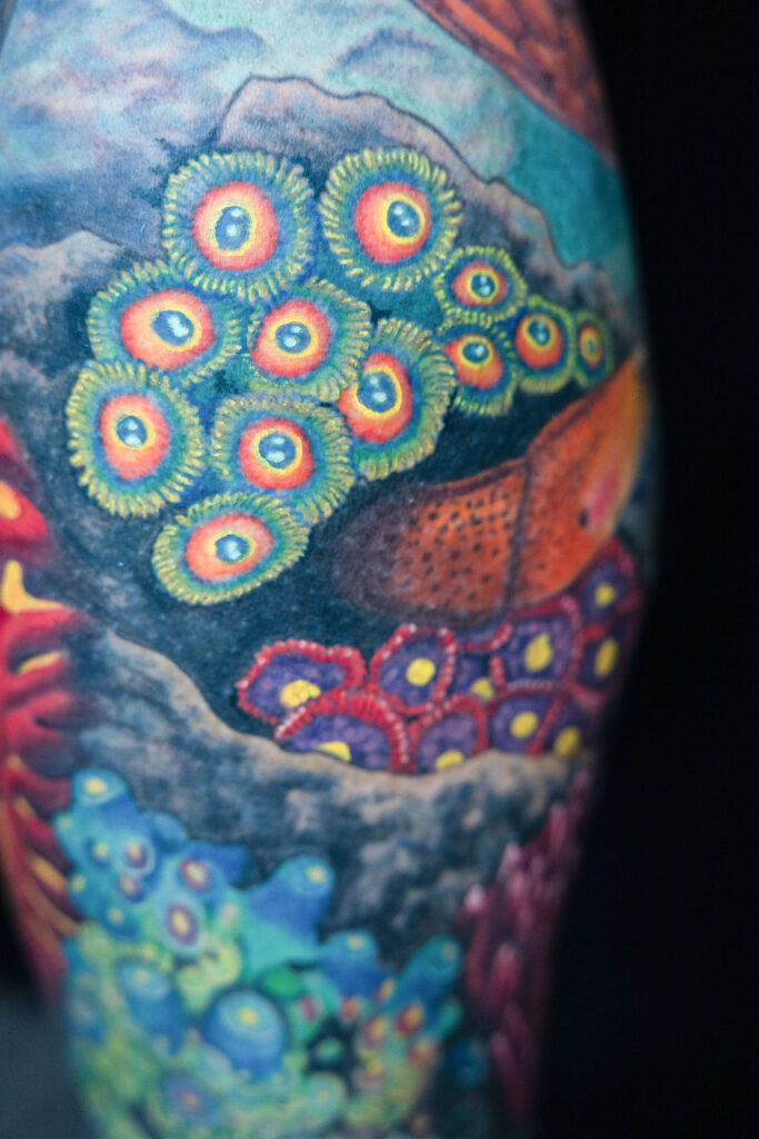 color realism coral tattoo, bright vivid colors with a eel looking fish, gobi watchman, done by a Houston tattoo artist