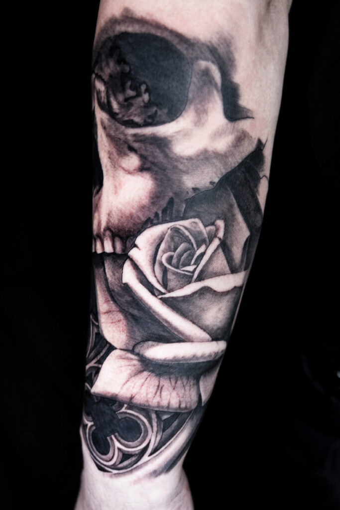 work in progress sleeve tattoo of a skull and rose, black and grey realism, very detailed, smooth shading, done by a Houston tattoo artist