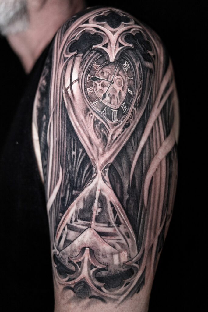 a black and grey tattoo of a morph between a clock or stopwatch and an hourglass done by a Houston tattoo artist