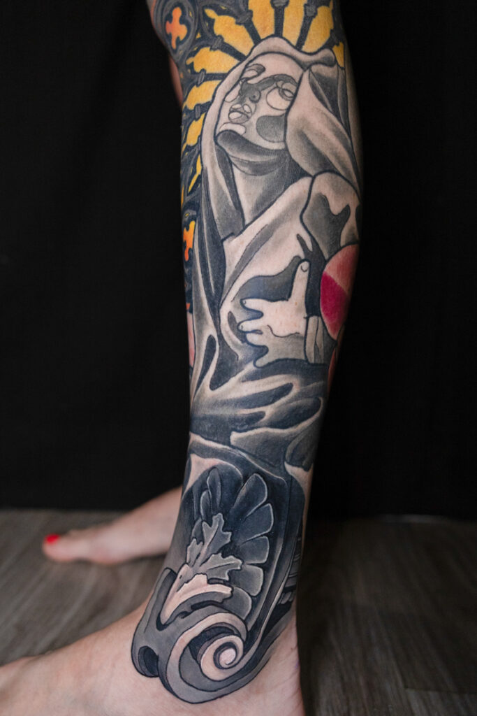 color illustrative tattoo on leg of a statue with filigree stylized, main imagery just grey and black
