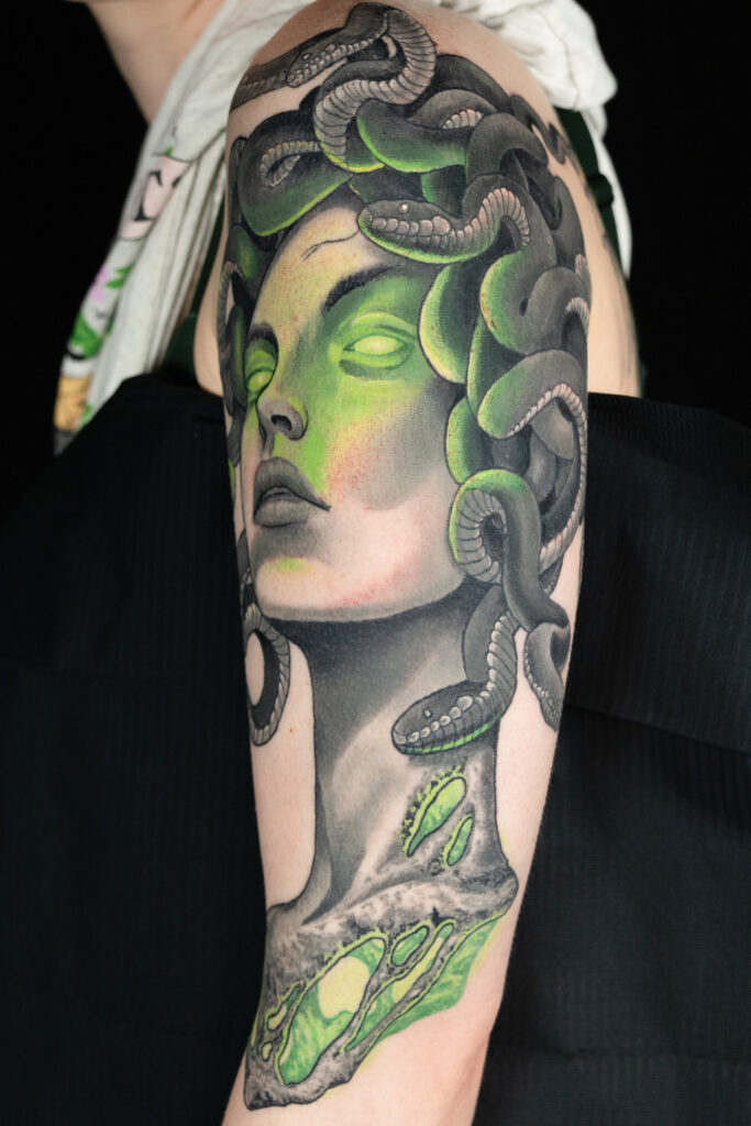 monochromatic green and grey illustrative realism tattoo of medusa, smooth shading with a textured glowing neck, done by a Houston tattoo artist