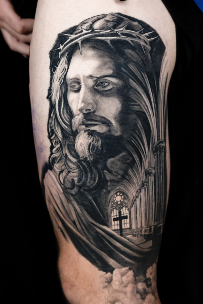 Black and grey tattoo of Jesus Christ with a cathedral church fading into his chest, done by an artist in houston