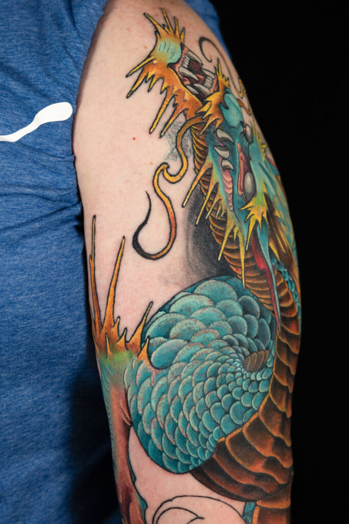 front shot of an illustrative color realism Japanese dragon. bright teals, done by a Houston tattoo artist