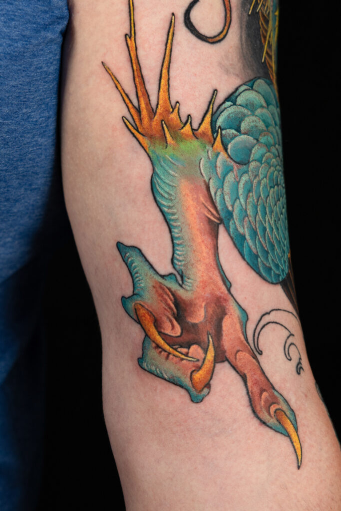 illustrative color realism tattoo of a Japanese dragon claw, teal scales and golden spiked and nails, done by Houston tattoo artist