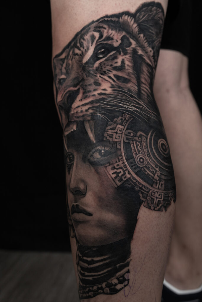black and grey tattoo of an Aztec woman with a tiger headdress and a aztec symbol on fading into her face