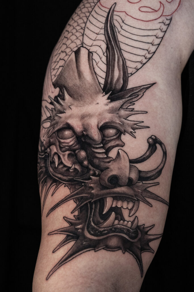 black and grey realism work in progress tattoo of a Japanese dragon head, lots of details and textures, done by Houston tattoo artist